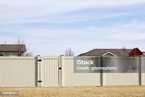 istock Tan colored vinyl fence spanning across a backyard 1135181671