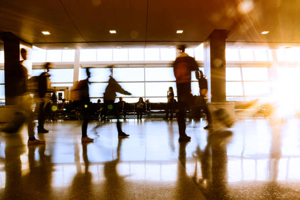 A long exposure image taken of the walkway and waiting area by a loading terminal in the Seattle / Tacoma airport in Washington state.  A bright setting sun shines through the large bay windows.