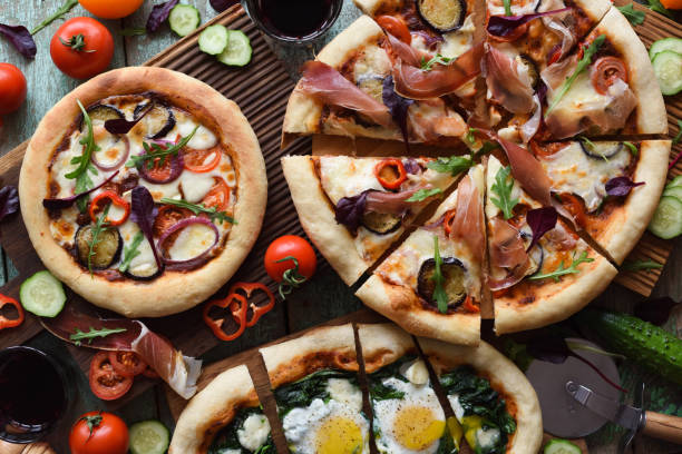 istock Rustic style pizza party. Homemade puffy pizzas with pancetta, aubergines, spinach, eggs, bell pepper and arugula served with raw ingredients on oak boards 1135182602