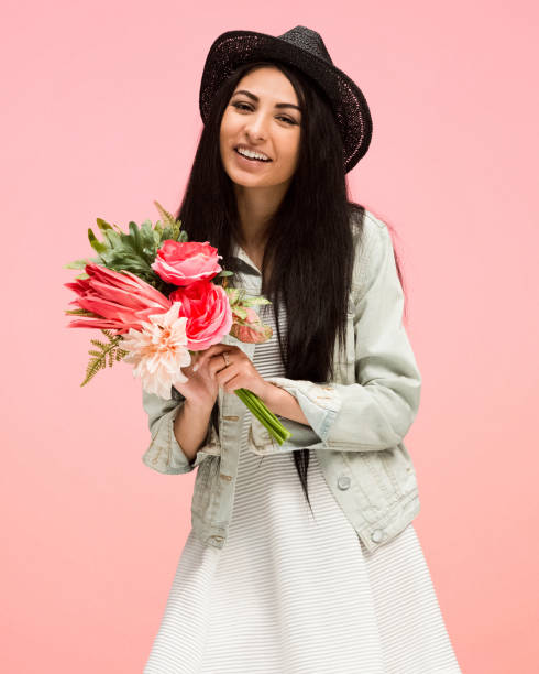 istock Beautiful female on pink background is holding arranged flowers 1135185113