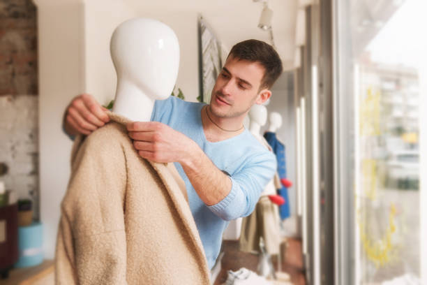 Man putting clothes on a mannequ in store.