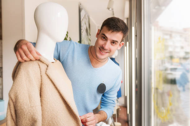 istock Young man putting clothes on a mannequin in store. 1135185481