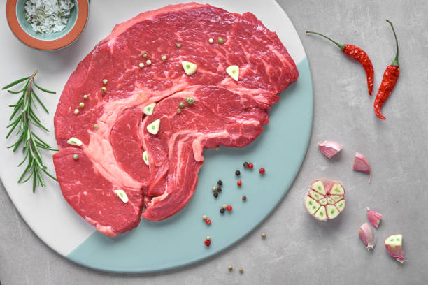 istock Raw steak meat with spices and herbs, flat lay on light stone background 1135186300