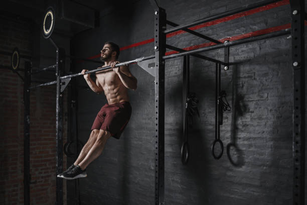 Athlete doing pull-ups at the gym Athlete doing pull-ups at the gym. Practicing calisthenics. Handsome man doing functional training. horizontal bar stock pictures, royalty-free photos & images