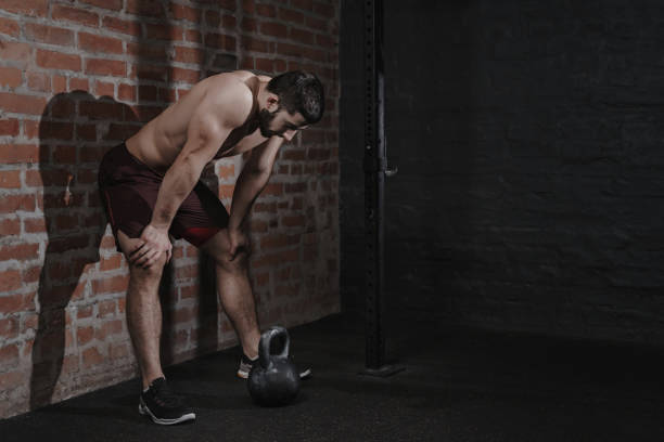 Athlete is leaning against the wall at the gym suffering breakdown to overcome Athlete is leaning against the wall at the gym suffering breakdown to overcome. Demotivation sport concept. Stress and fatigue in sport. Kettlebell training. Copy space. BURNING CALORIES stock pictures, royalty-free photos & images