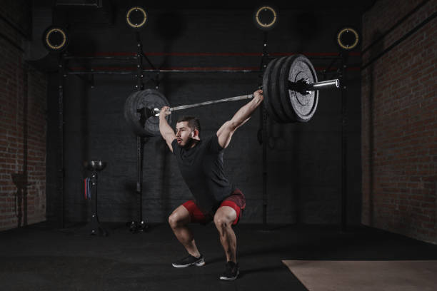 istock Man doing squats with heavy barbell overhead at the gym 1135187822