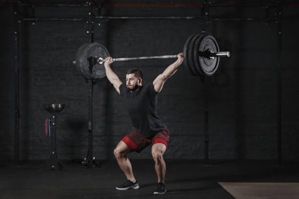 istock Young athlete lifting barbell overhead at the gym 1135187857