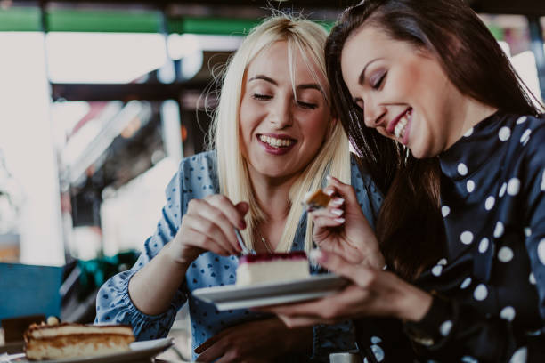 female friends eating cakes together at cafe - food shopping imagens e fotografias de stock