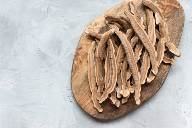 Slices of dried lingzhi mushroom, also called Reishi, on a wooden board Slices of dried lingzhi mushroom, also called reishi or Ganoderma Lucidum, on a wooden board, grey background. Chinese traditional medicine product. Copy space. ganoderma lucidum stock pictures, royalty-free photos & images