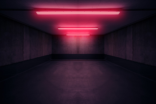 dark underground room with red neon light in basement or parking lot -