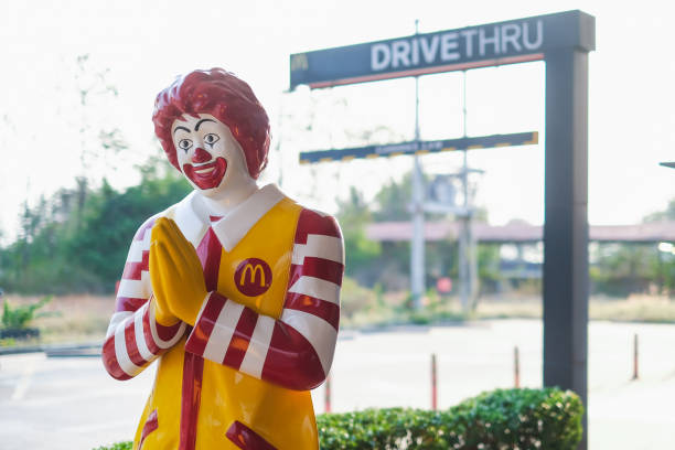 накхон сазан, thailand - 01 марта 2019: талисман ресторана mcdonald's, рональд макдональд, стоящий перед диском mcdonald's через знак обслуживания - bangkok mcdonalds fast food restaurant asia стоковые фото и изображения