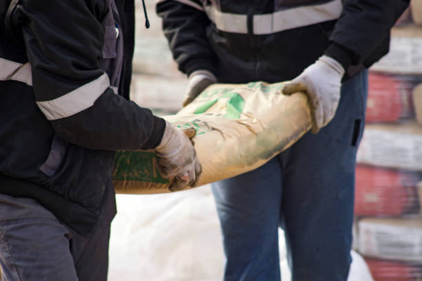 Two construction workers carry a bag of cement midsection close up at the warehouse Two construction workers carry a bag of cement midsection close up at the warehouse cement bag stock pictures, royalty-free photos & images