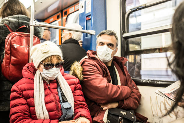 hombre y mujer madurado llevando máscara protectora en el tren. - pig flu fotografías e imágenes de stock