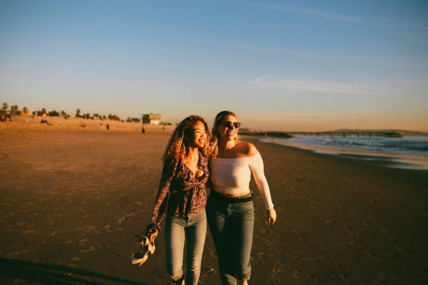 Vintage toned, warm colored portrait of a young mixed Latina woman with her female friend, watching the beautiful sunset on the Venice beach in Los Angeles, California. Friendship or couple concepts in the beautiful California sunset.