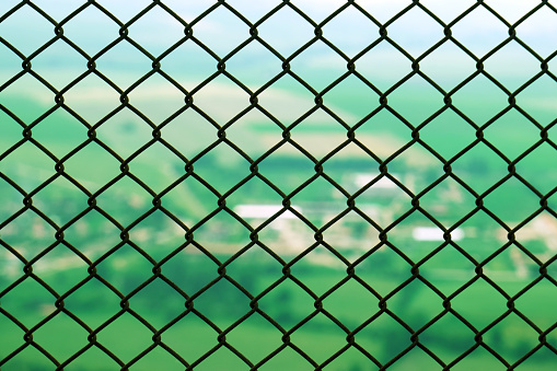 Protective restrictive metal mesh on top of the mountain. Beautiful view of the green summer valley from the top of the mountain