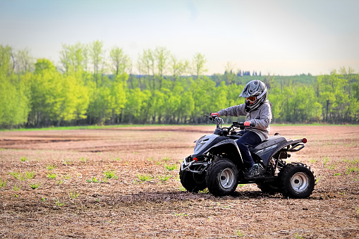 A young boy quading in a spring field.