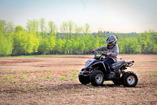 A young boy quading in a spring field A young boy quading in a spring field. quadbike photos stock pictures, royalty-free photos & images
