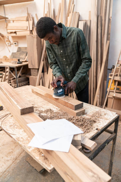 istock Young black carpenter using a sander on a piece of wood 1135209253