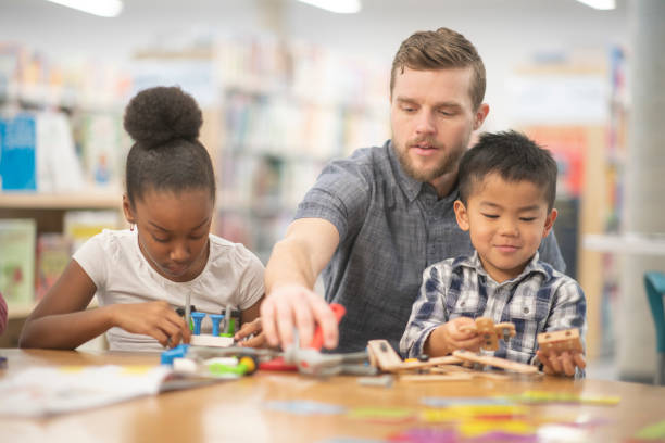 istock Male teacher helping his young students 1135210369