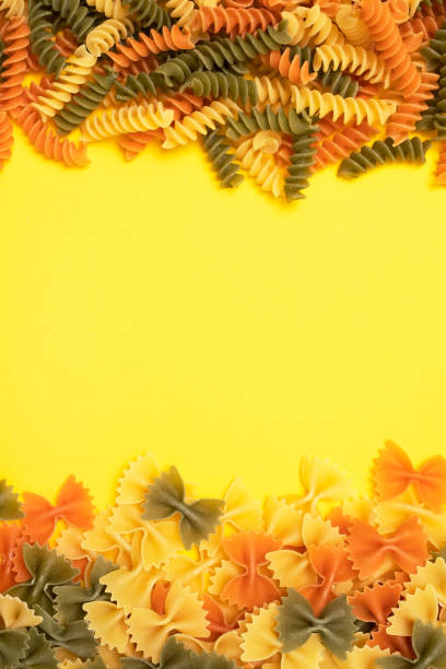 istock Fusilli and farfalle pasta on yellow background. Top view. 1135210622