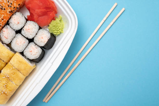 istock Top view on sushi set at colored background. Plate with rolls, ginger and vasabi 1135210624