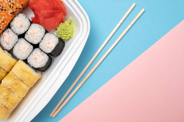 istock Top view on sushi set at colored background. Plate with rolls, ginger and vasabi 1135210674