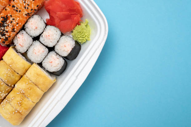 istock Top view on sushi set at colored background. Plate with rolls, ginger and vasabi 1135210706
