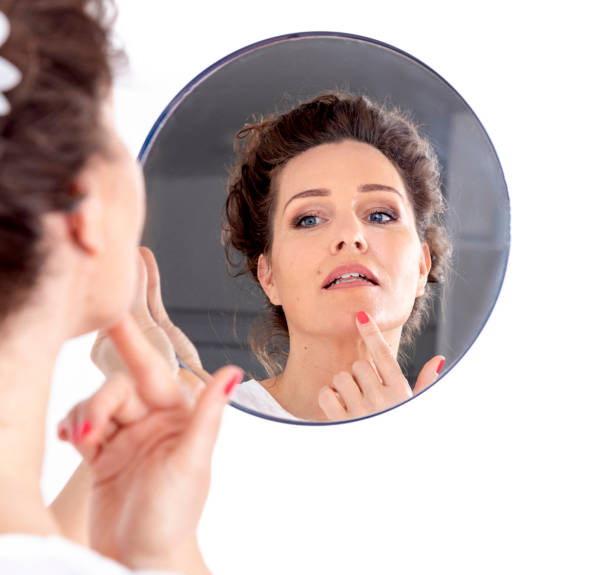 istock Middle-aged woman looks at her face in a mirror 1135211592