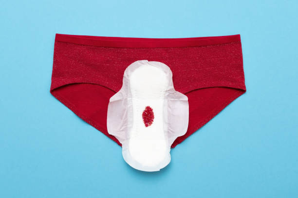 goutte rouge des perles sur le pantalon sur le fond bleu. période de menstruation - menses photos et images de collection