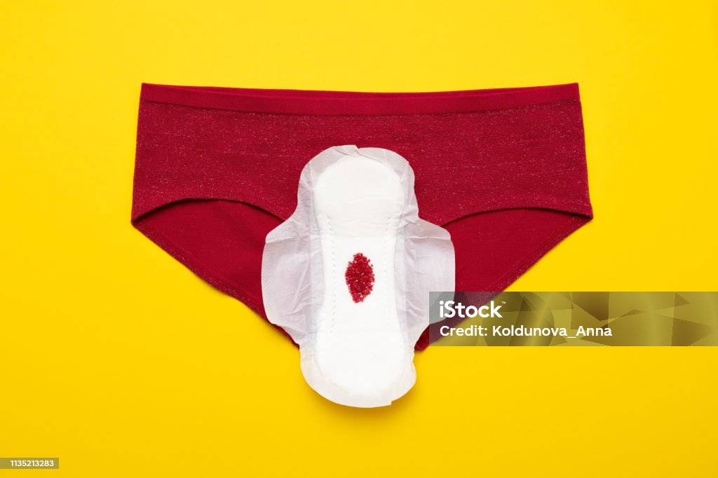 Red drop from beads on pants on yellow background. Menstruation period Menstruation period concept. Red drop from beads on pants on yellow background Cycle - Vehicle Stock Photo