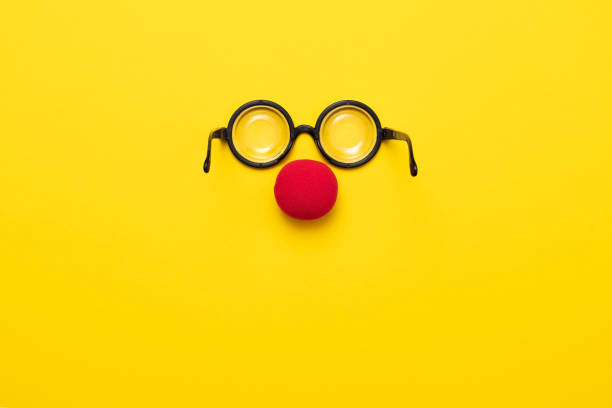 funny glasses, red clown nose and tie lie on a colored background, like a face. - clowns nose imagens e fotografias de stock