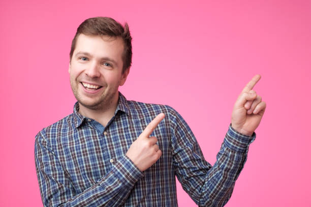 istock Happy beautiful bearded guy looking at camera, smiling and pointing aside 1135213919