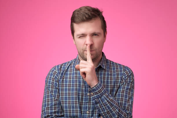 istock Serious good looking male keeps fore finger on lips, tries to keep conspiracy, 1135214919