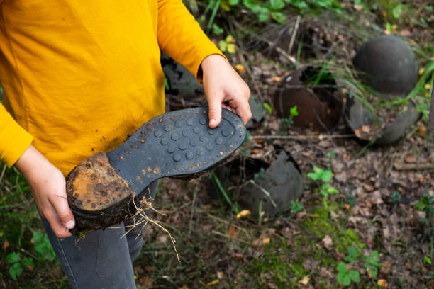istock Kid showing old soldier shoe from second world war that he has found in forest 1135215372
