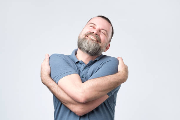 Funny selfish mature european guy in blue shirt cuddling himself stock photo