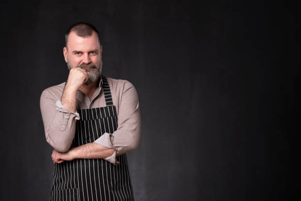 istock Mature handsome man with beard wearing apron with a confident expression 1135216139