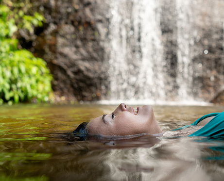 Portrait of a happy woman relaxing by swimming in a lake and floating on the water â lifestyle concepts