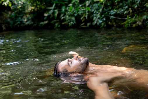 Portrait of a happy man relaxing and floating in the water â lifestyle concepts