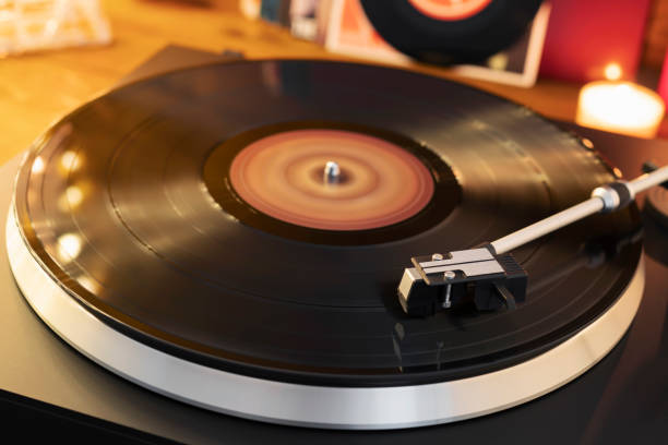 istock Turntable player with background of a stack of audition records and a Christmas tree. Sound technology DJ. Black vinyl record and stylus with needle. Christmas lights bokeh reflected on label surface 1135218163