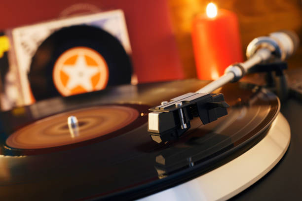 istock Turntable player with background of a stack of audition records and a Christmas tree. Sound technology DJ. Black vinyl record and stylus with needle. Christmas lights bokeh reflected on label surface 1135218172