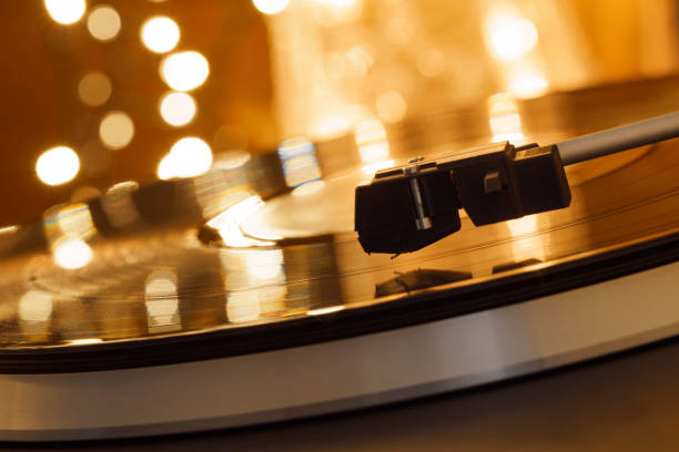istock Turntable player with background of a stack of audition records and a Christmas tree. Sound technology DJ. Black vinyl record and stylus with needle. Christmas lights bokeh reflected on label surface 1135218174