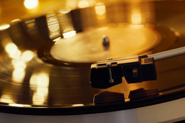 istock Turntable player with background of a stack of audition records and a Christmas tree. Sound technology DJ. Black vinyl record and stylus with needle. Christmas lights bokeh reflected on label surface 1135218177