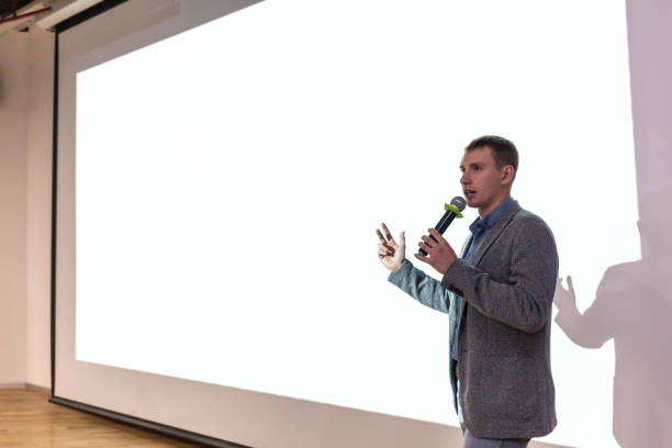istock A man near the white screen of the projector with a micraphone talks about the project. 1135233054