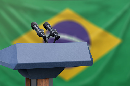 Podium lectern with two microphones and Brazil flag in background