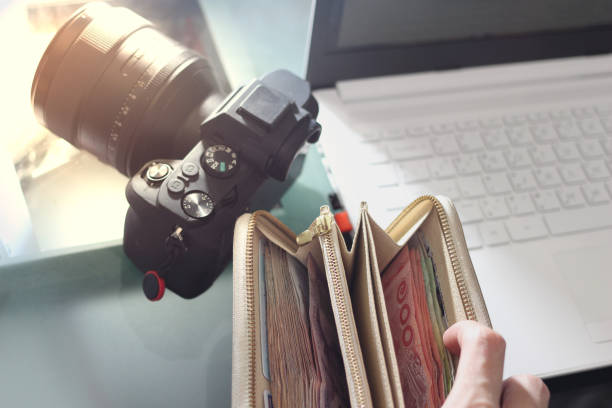 istock full of money wallet hand and notebook computer on blur camera background with sun light 1135238254