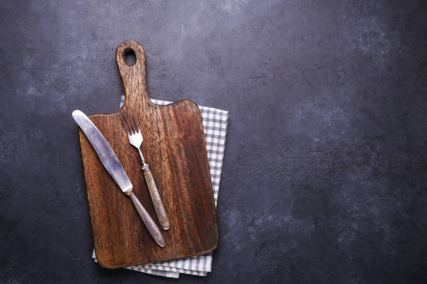 istock Dark stone table with cutting board and linen napkin Vintage fork and knife Copy space 1135239340