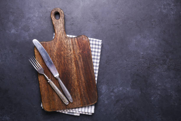 istock Dark stone table with cutting board and linen napkin Vintage fork and knife Copy space 1135239347