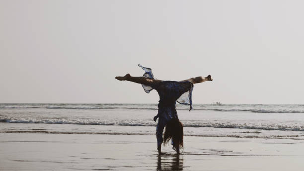 Young gymnast woman doing handspring on sandy beach Vintage image of young gymnast woman doing handspring on sandy beach handspring stock pictures, royalty-free photos & images