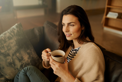 Shot of a beautiful young woman relaxing with a cup of coffee at home