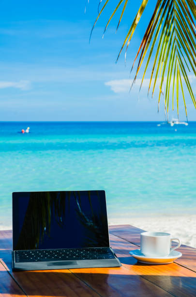 istock Laptop and coffee under palm tree on tropical beach 1135250027